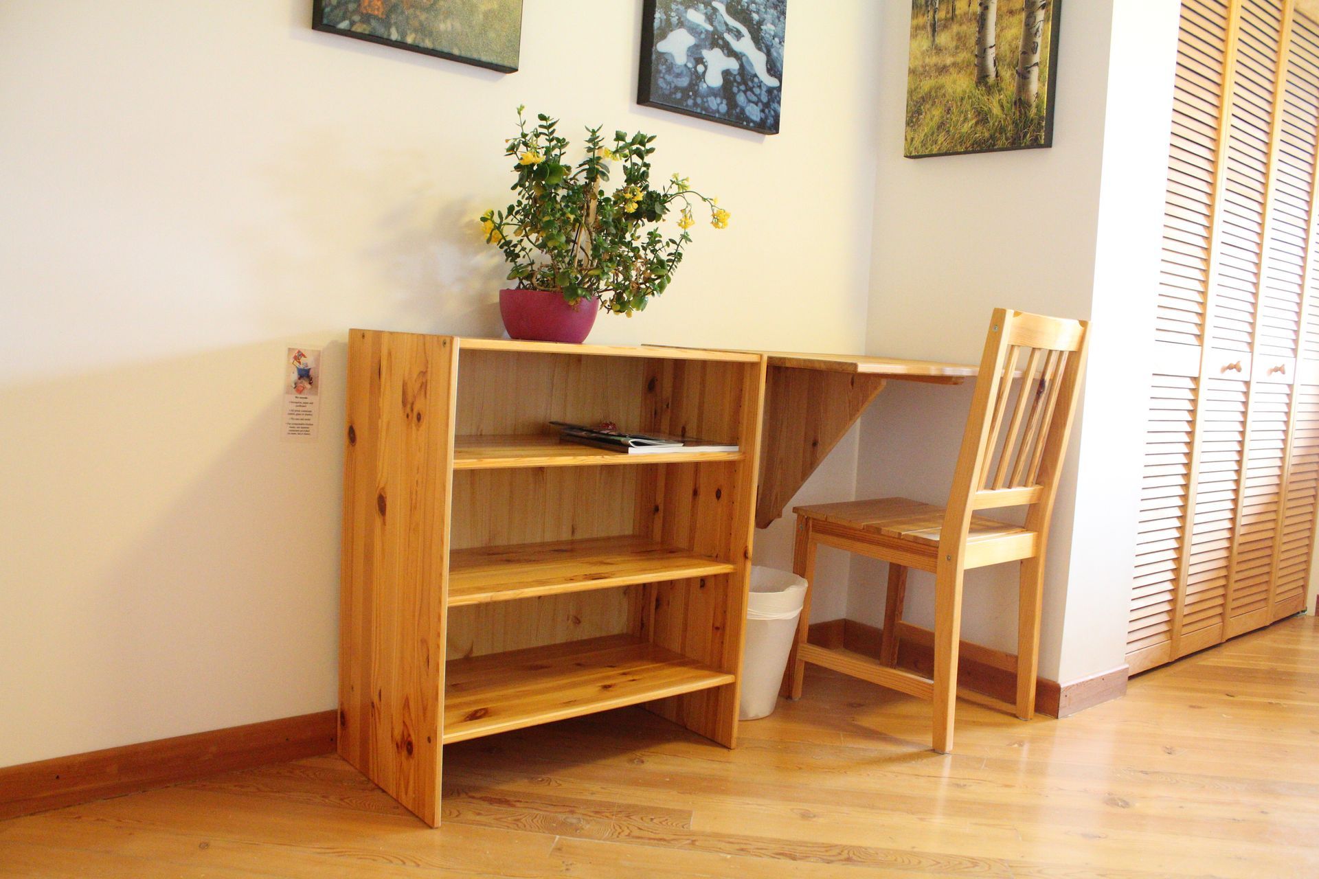 A wooden desk with a chair and a vase of flowers on it