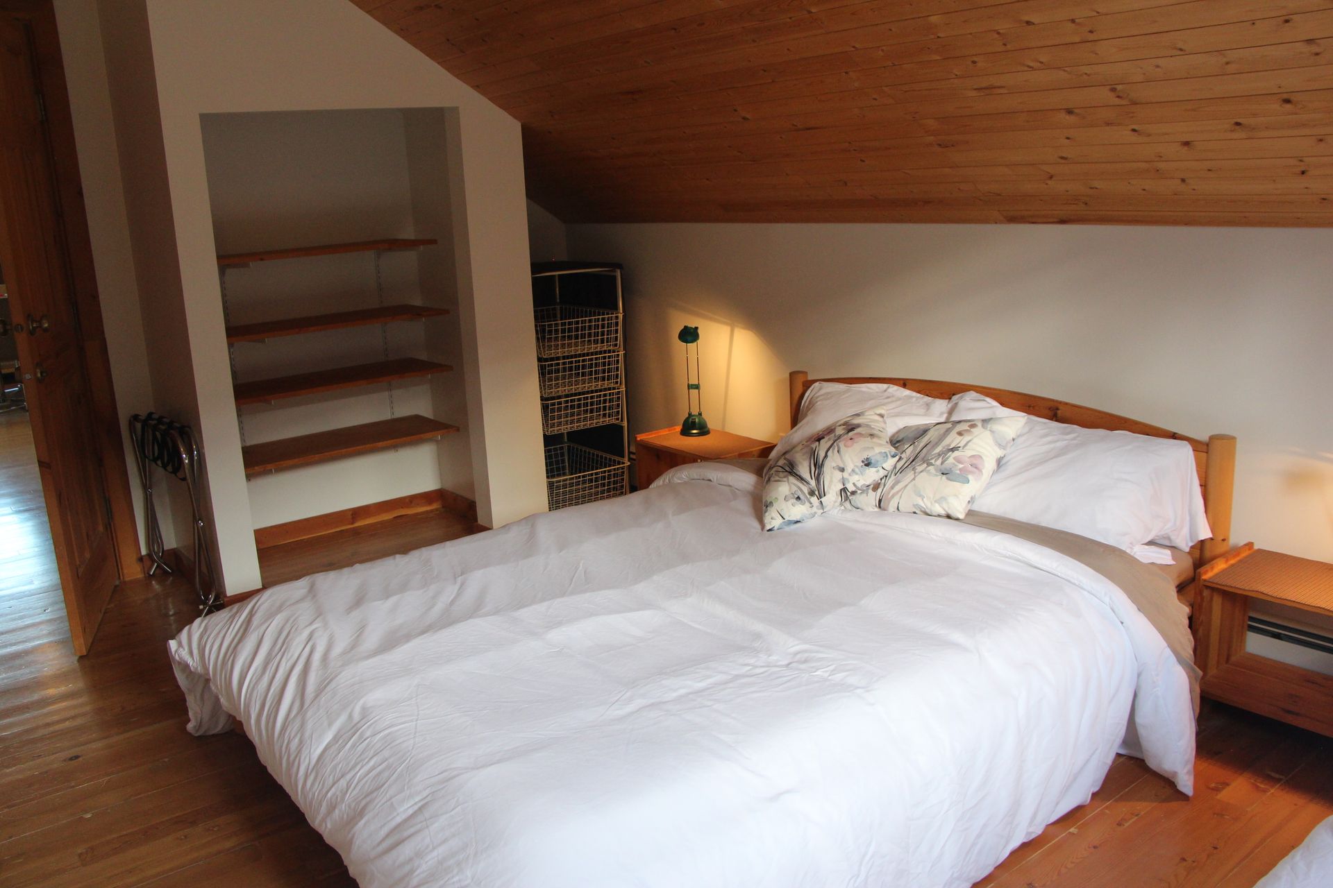 A bedroom with a large bed and a wooden ceiling.