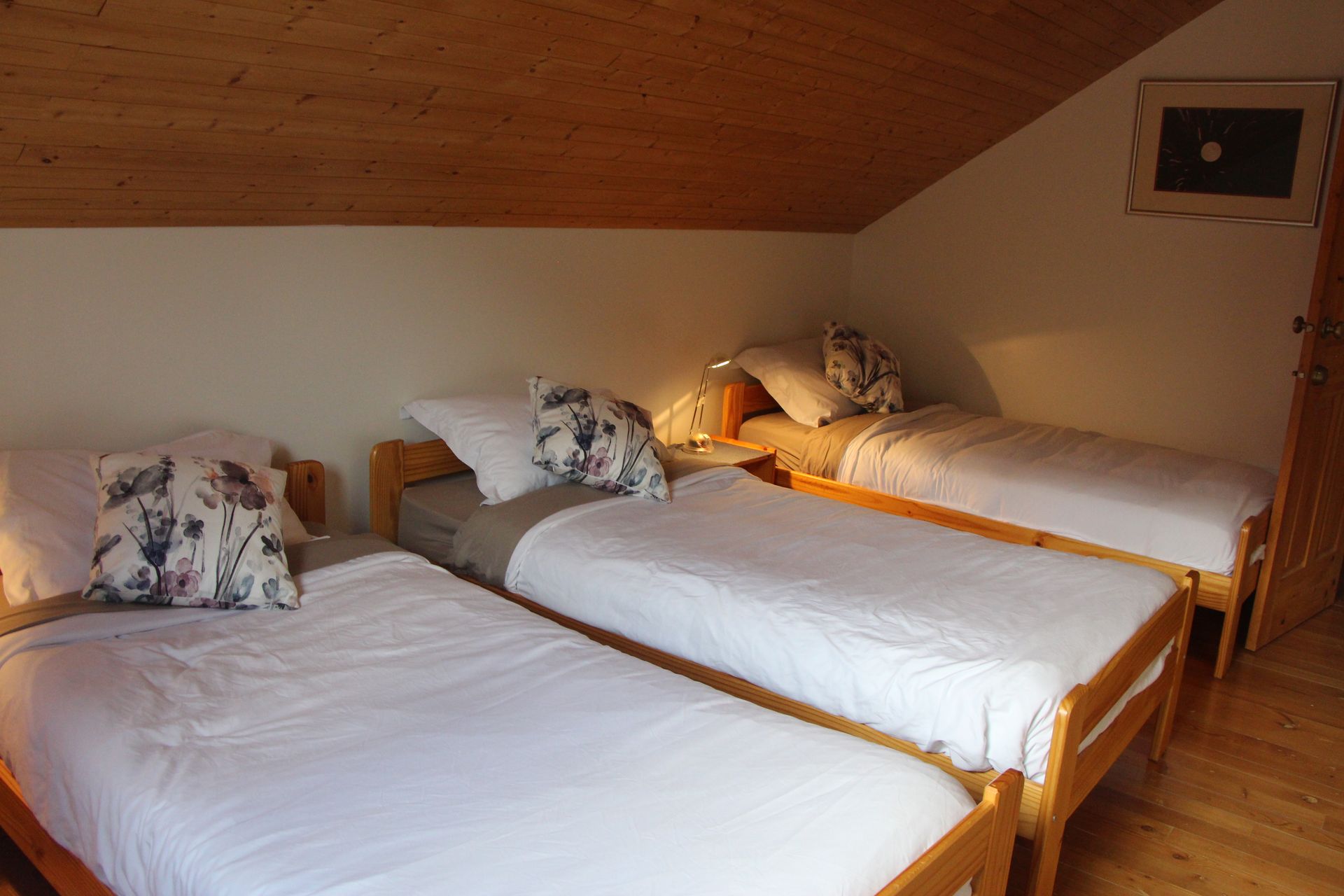 A bedroom with three beds and a wooden floor.