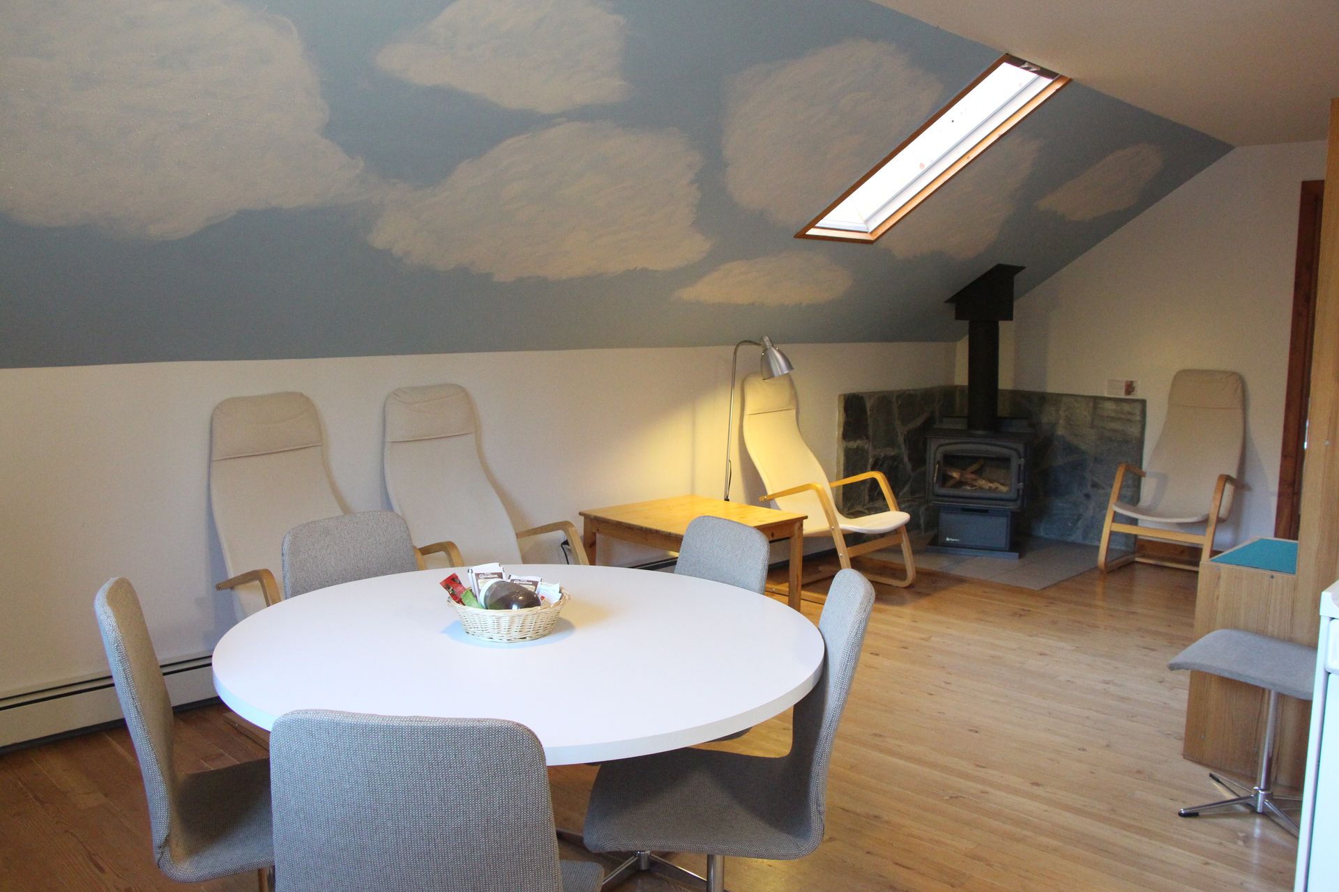 A living room with a round table and chairs and a sky painted on the ceiling