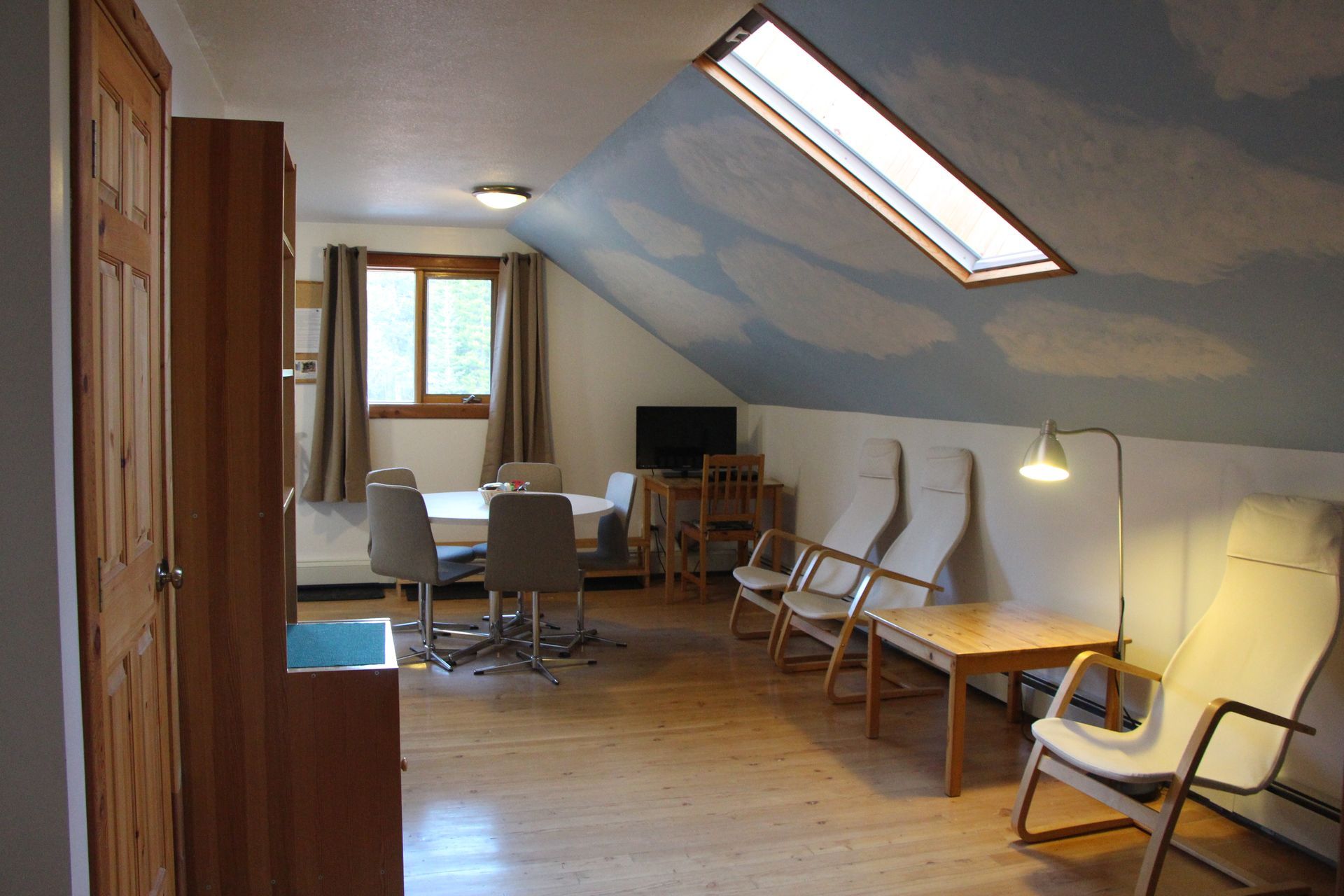 A living room with a skylight and a table and chairs