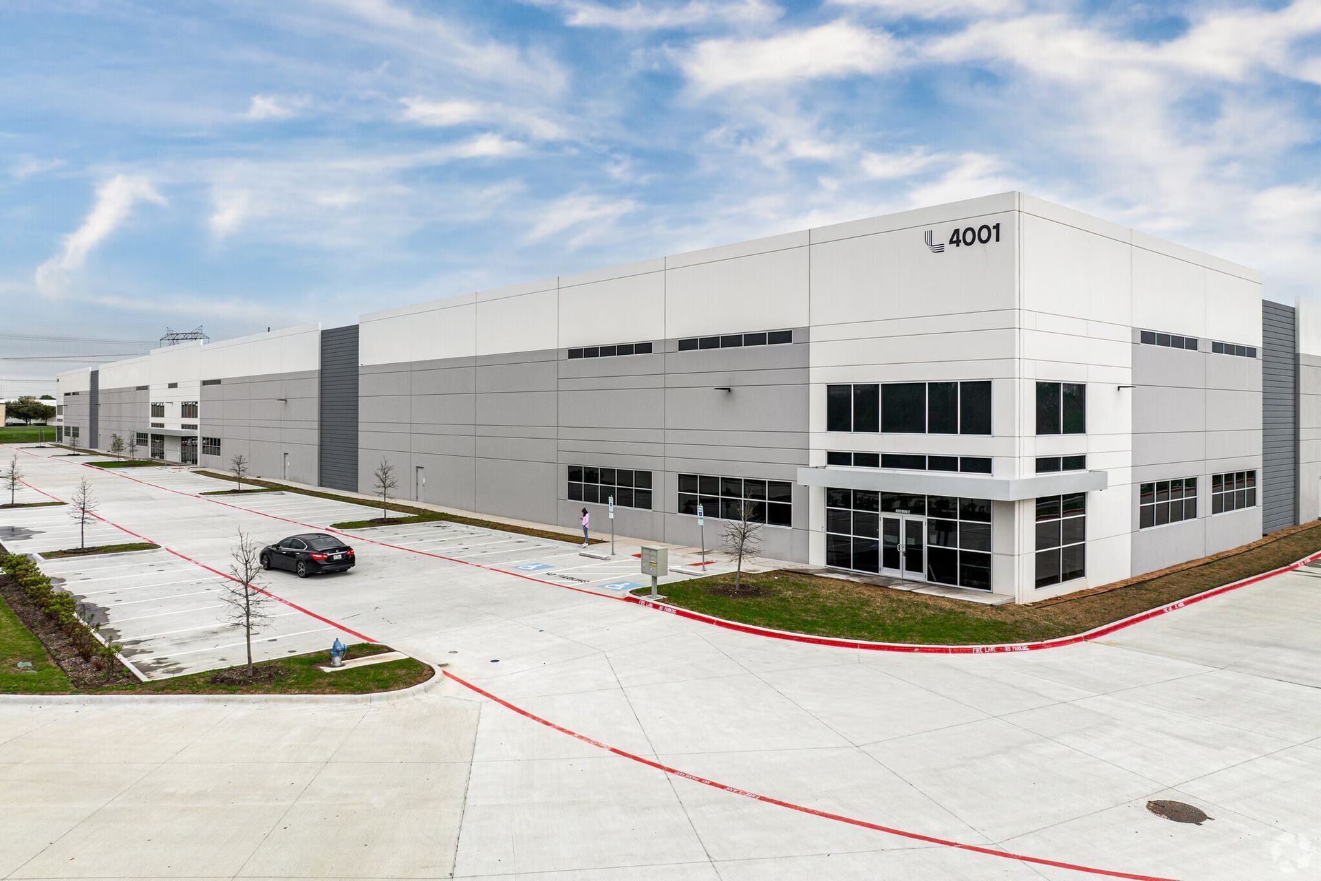 Large modern industrial building with gray and white facade under a blue sky.