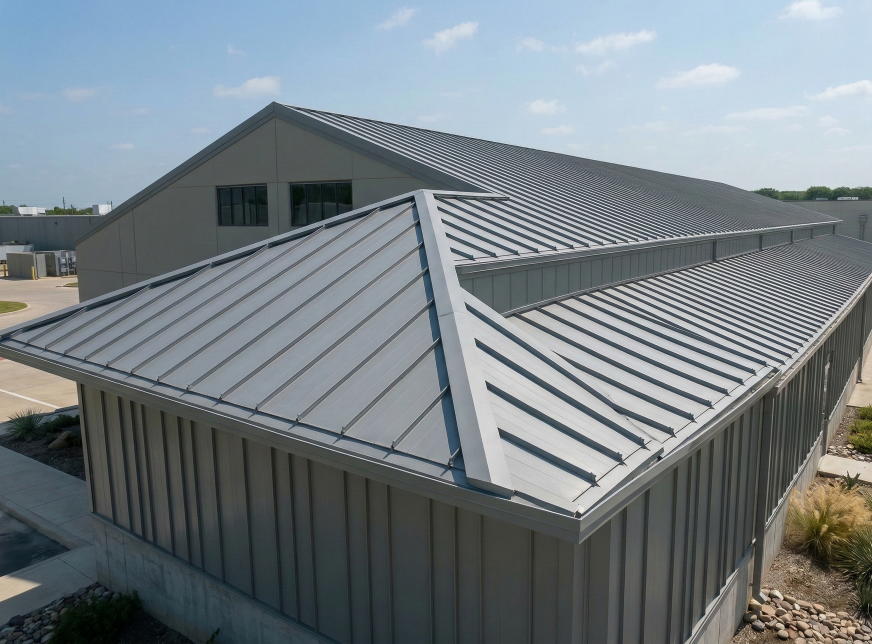 Metal roof of a building with multiple angled planes, viewed from above, on a sunny day.