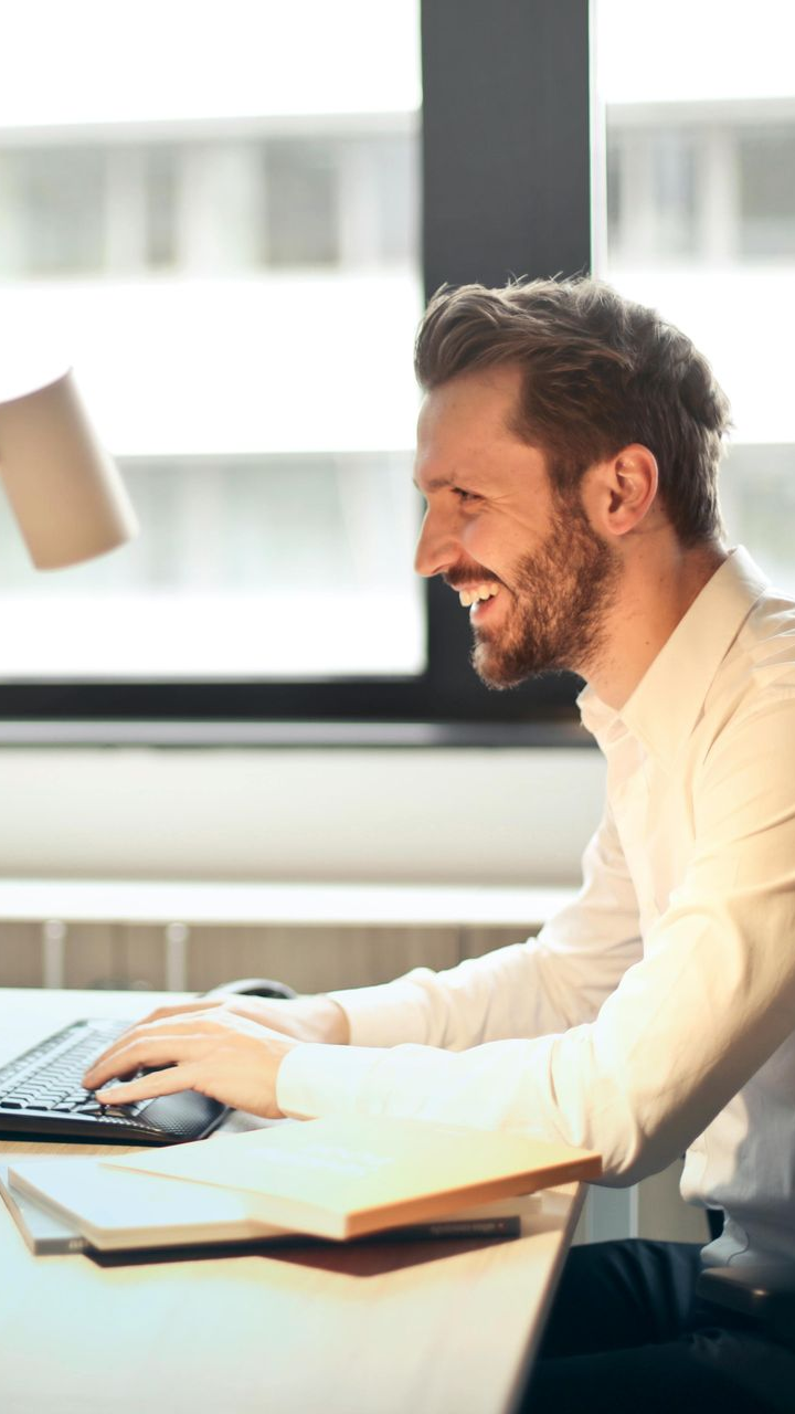 Two women are sitting at a table looking at a laptop computer.
