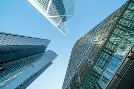 Low-angle view of three modern glass skyscrapers against a clear, light blue sky.
