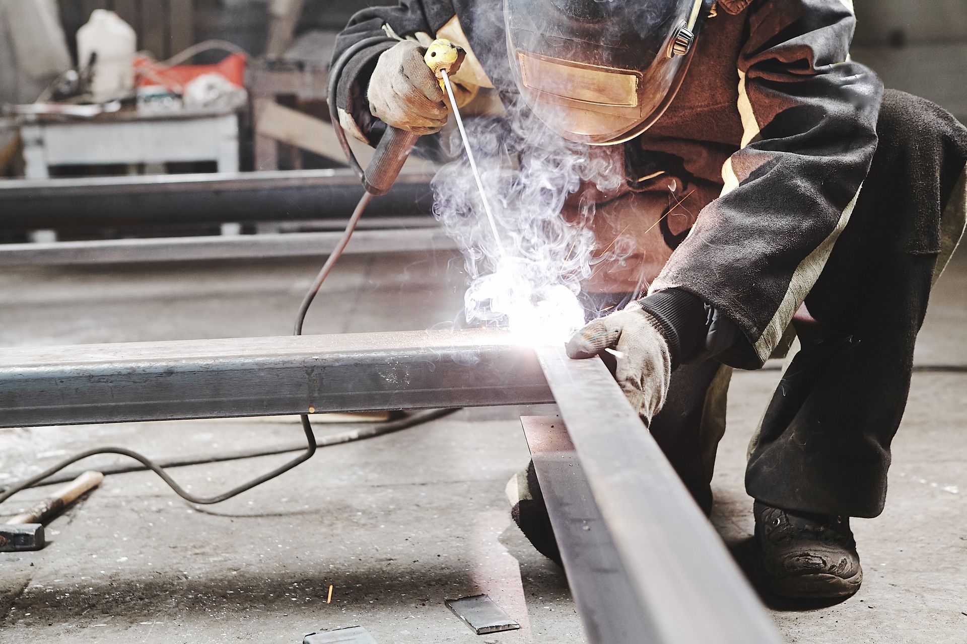 Image of a person welding together two metal beams and wearing protective gear