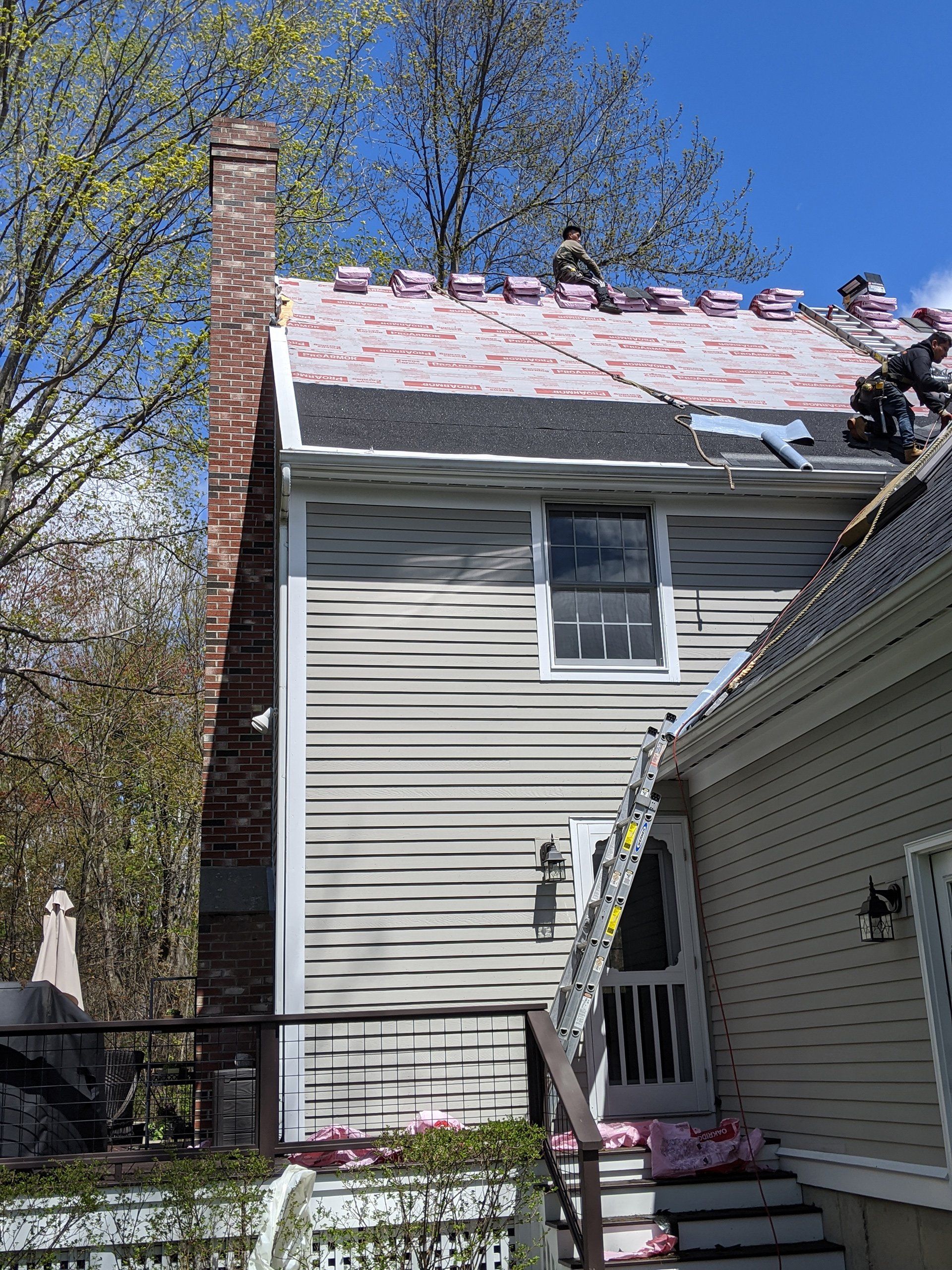 Roofing Company Workers Installing Waterproof Layers During Roof Replacement