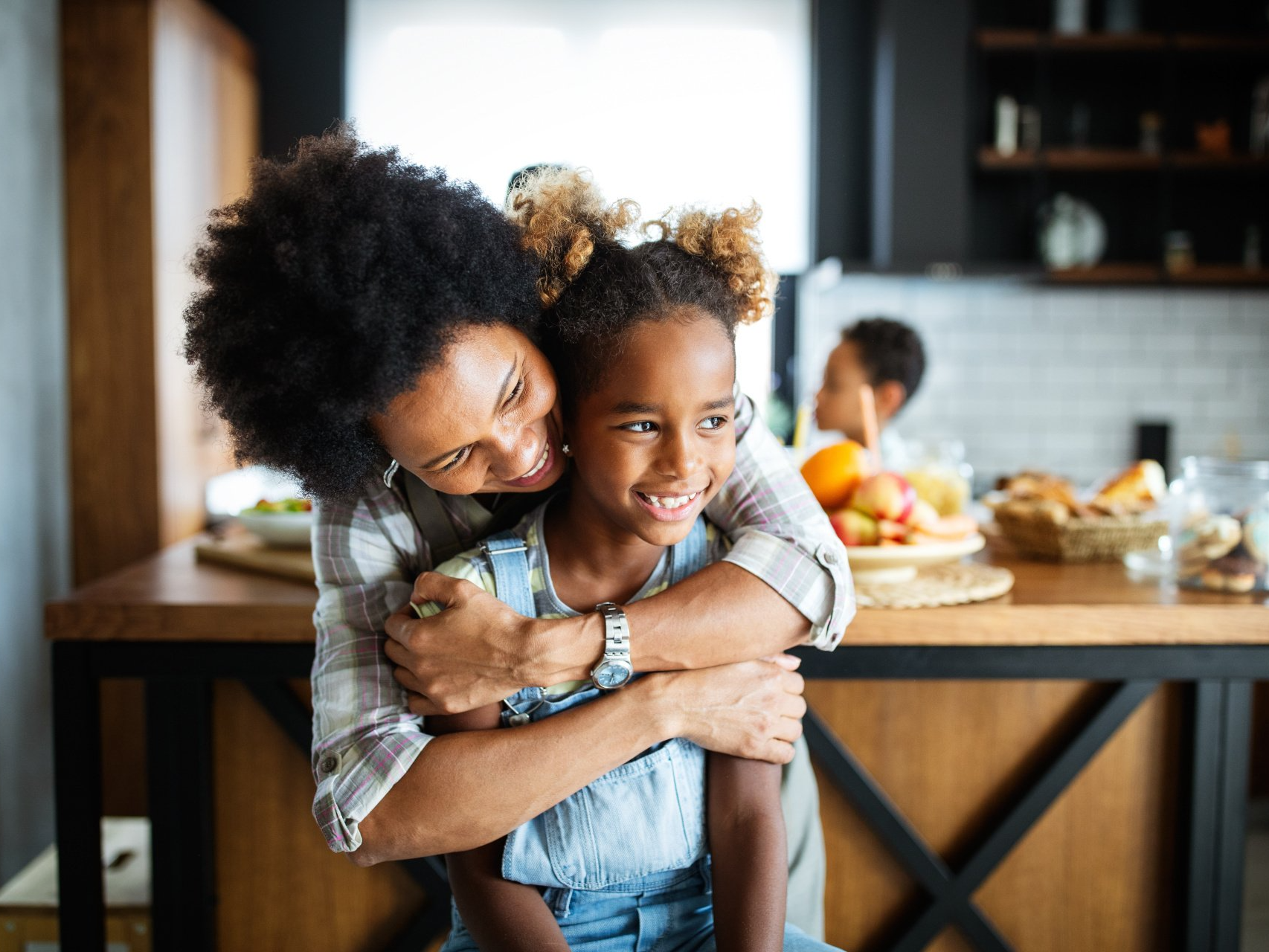 mother hugging daughter in the kitchen smiling