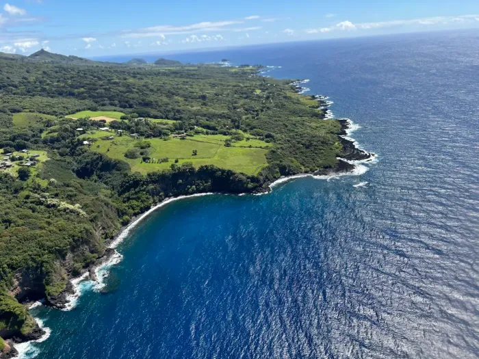 Aerial view of a lush green island coastline with a deep blue ocean.