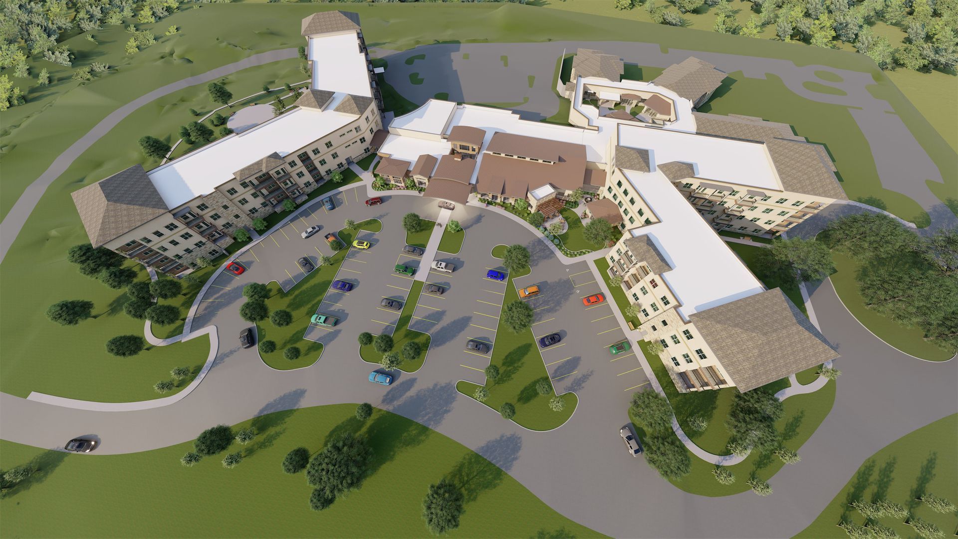 Overhead view of a multi-winged building with parking, landscaping, and a central entrance. Brown roof, green grounds.