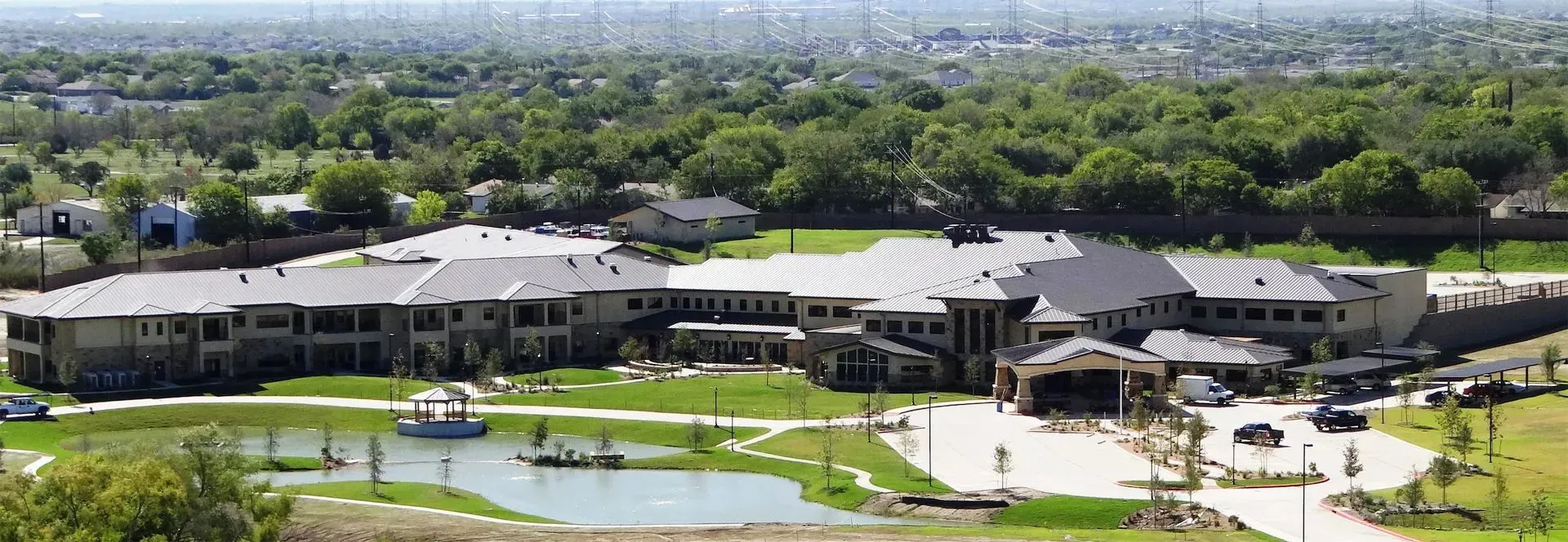 A rendering of a large senior care center surrounded by trees and a path.