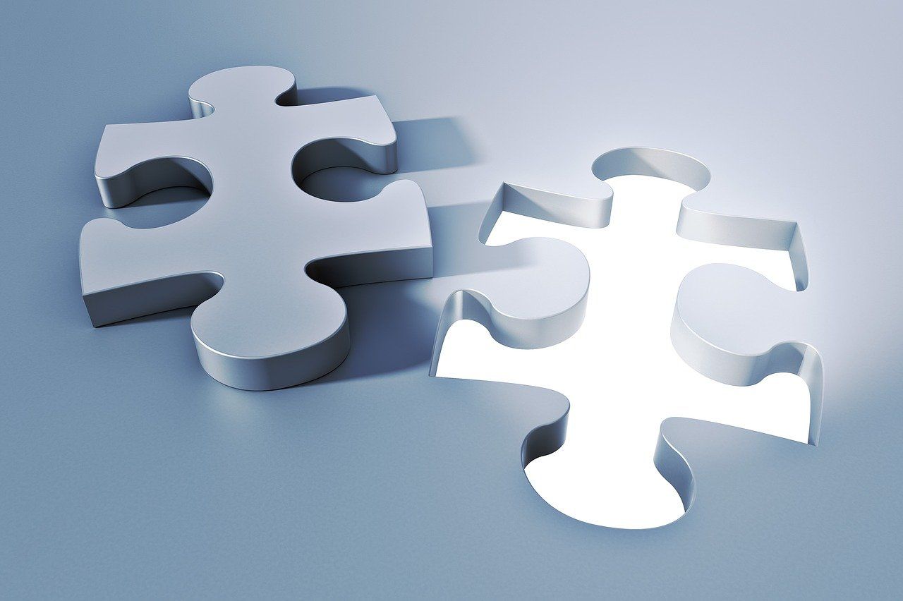 Two white puzzle pieces are sitting next to each other on a blue surface