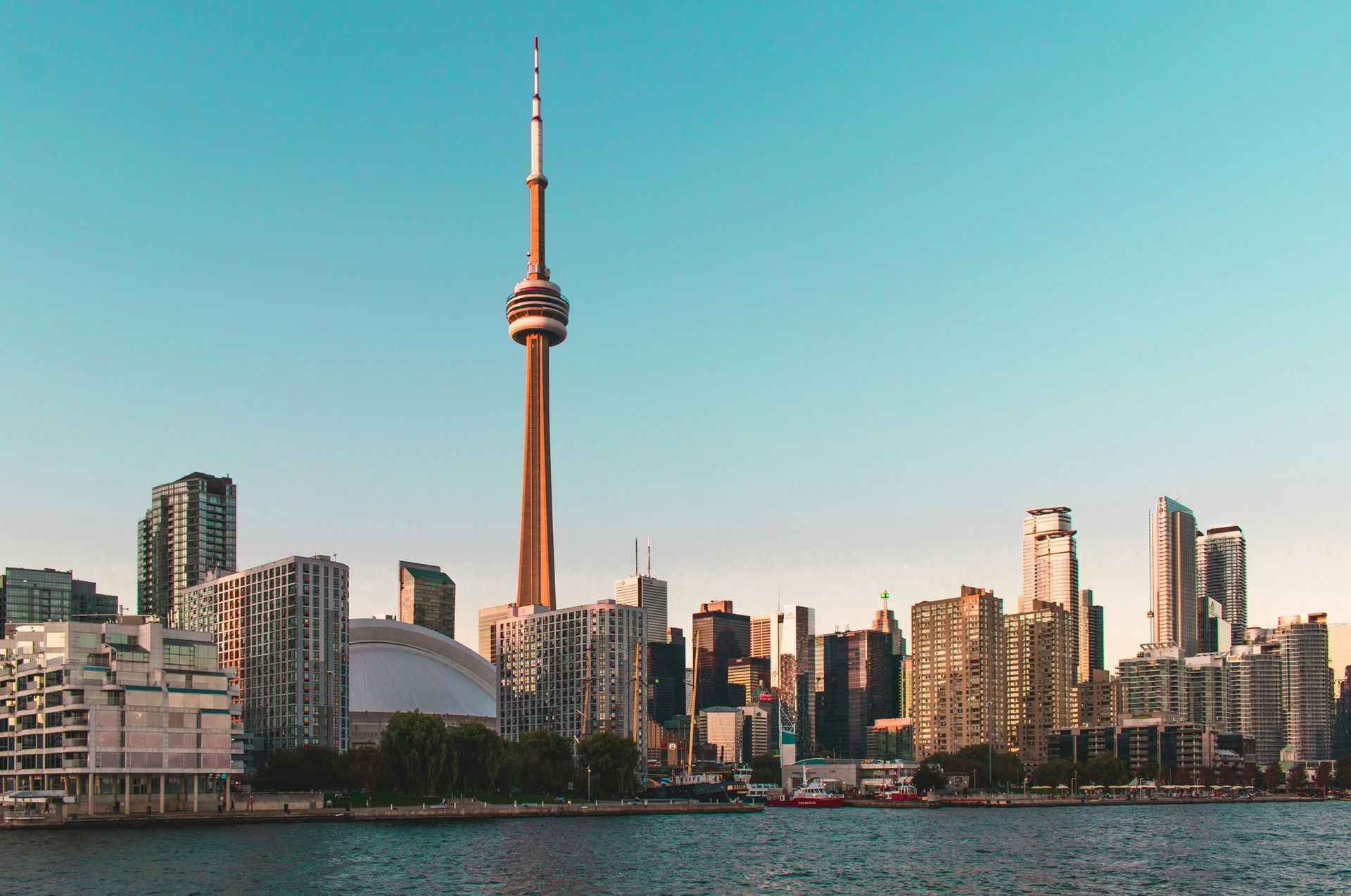Toronto skyline with CN Tower, against a clear, blue sky, viewed from the water.