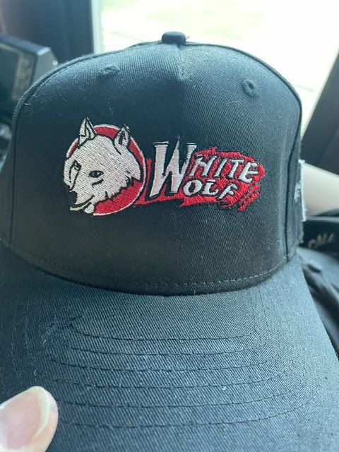 A black baseball cap featuring an embroidered white wolf head inside a red circle next to the red text 