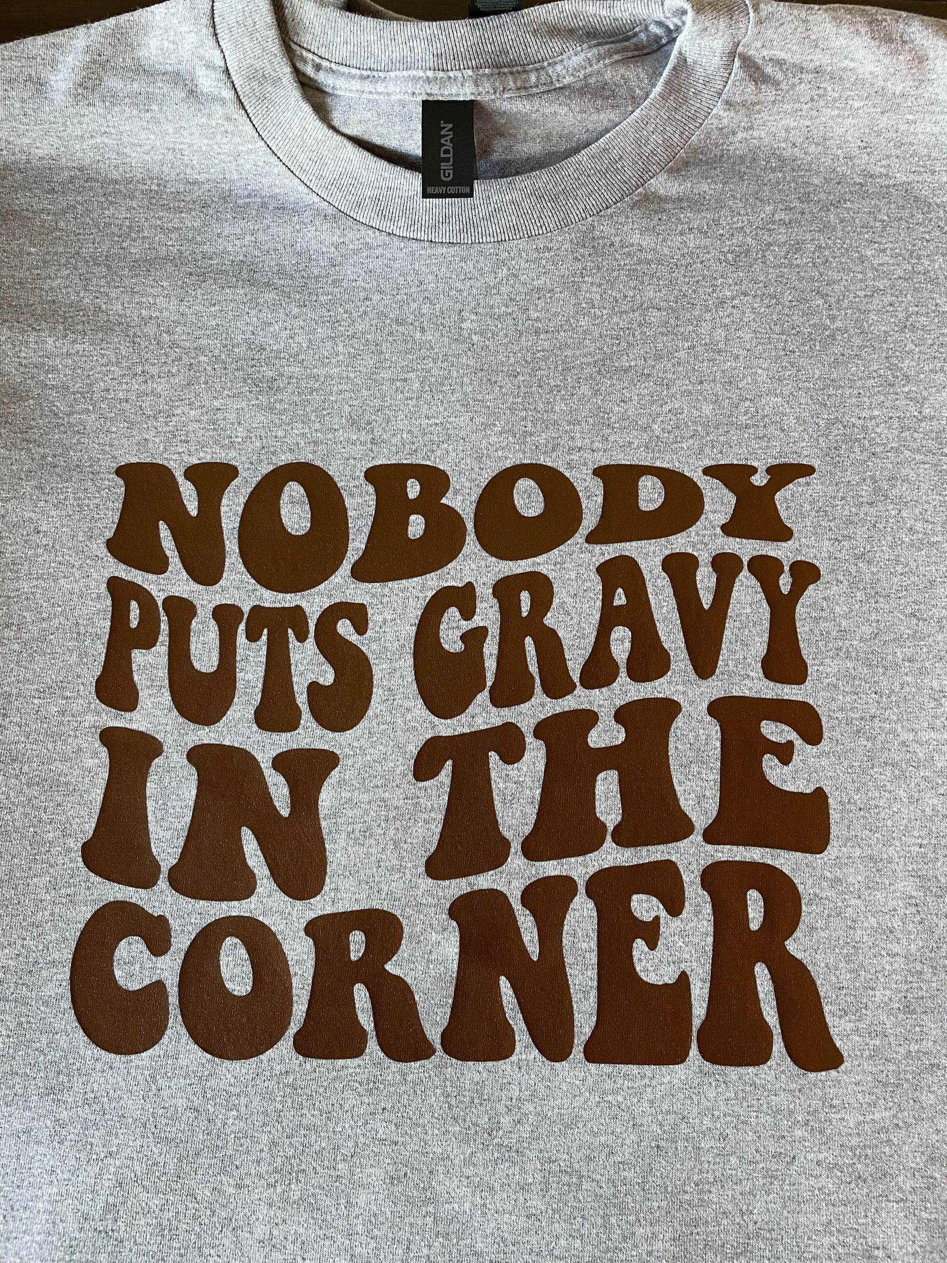 A grey t-shirt featuring brown, wavy-style text that reads: 