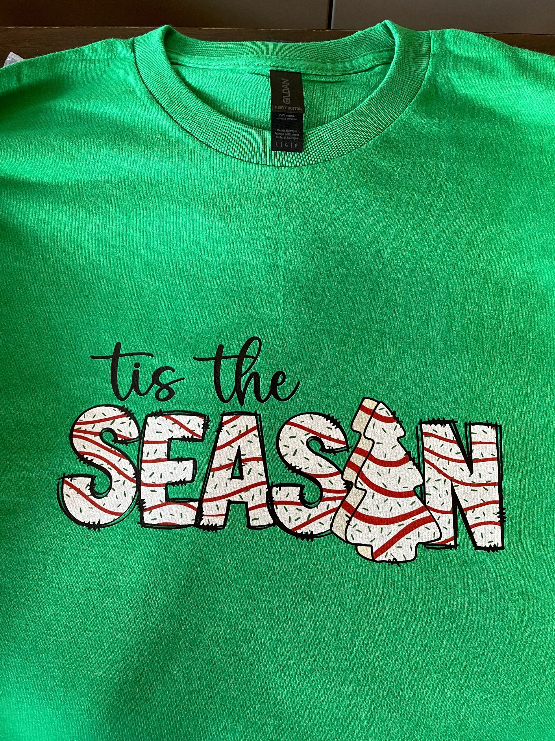 A bright green long-sleeve shirt with “tis the SEASON” printed in white, red-striped letters; the 