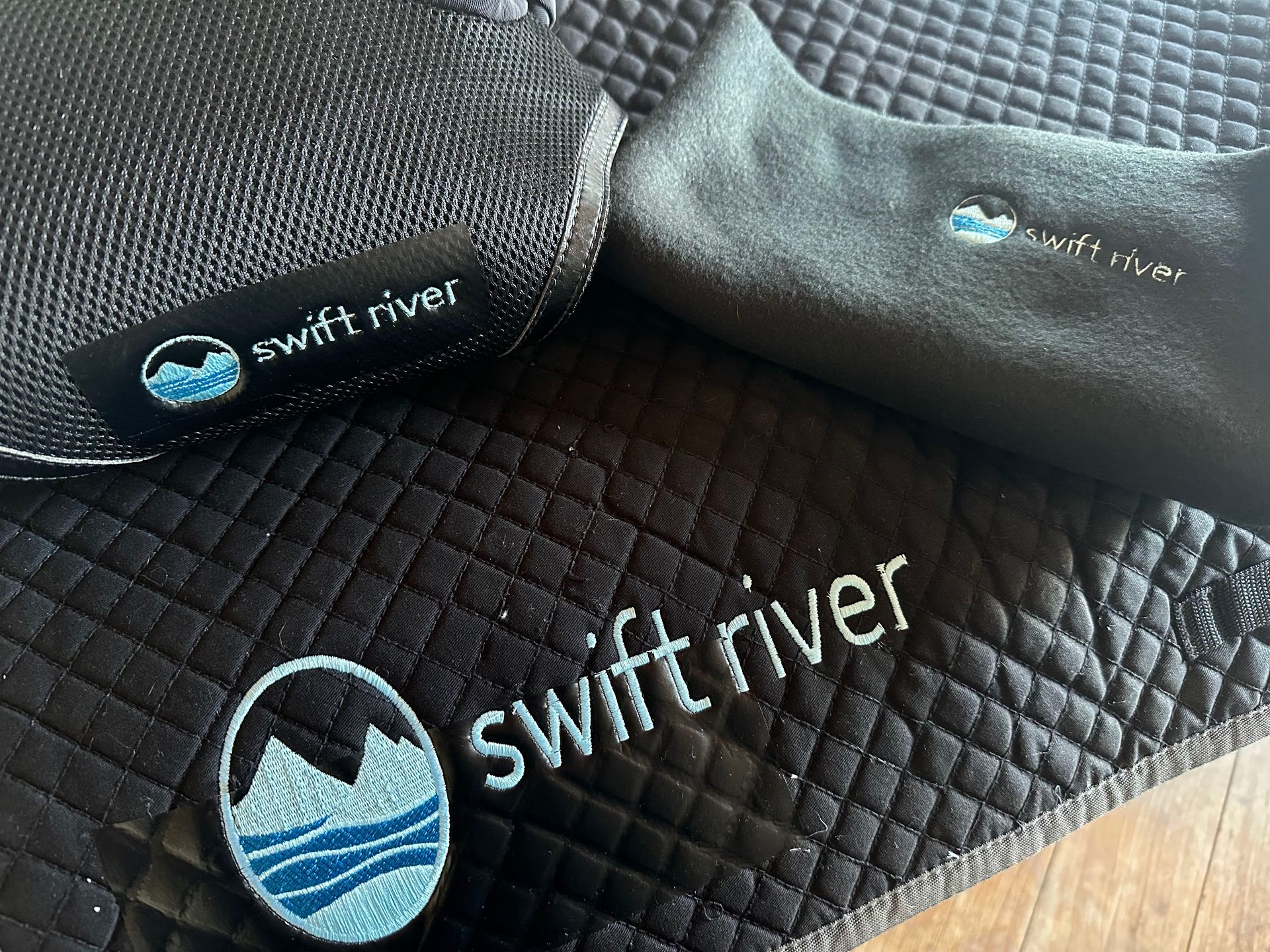 Black, diamond-quilted equestrian saddle pad featuring an embroidered 