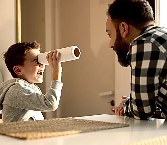 A man and a boy are playing with a paper towel tube.