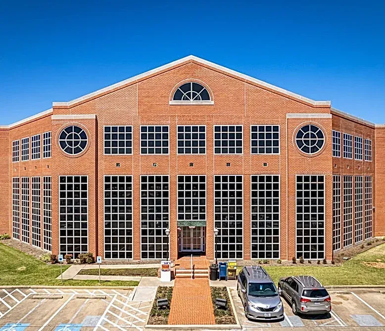 A large brick building with a lot of windows and cars parked in front of it.