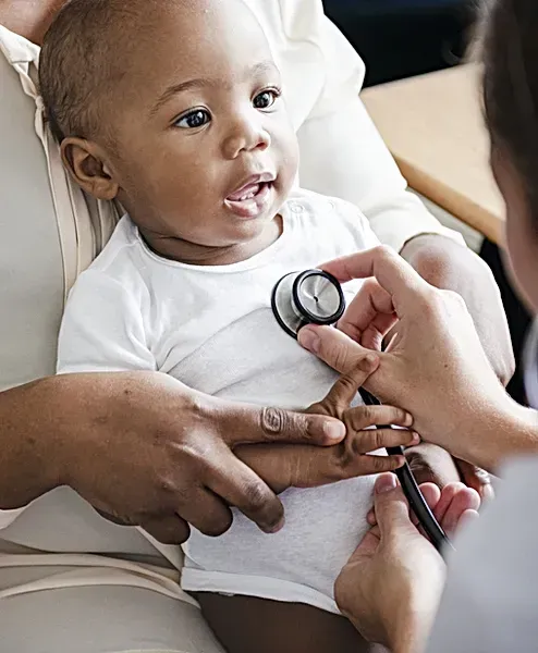 A baby is being examined by a doctor with a stethoscope.