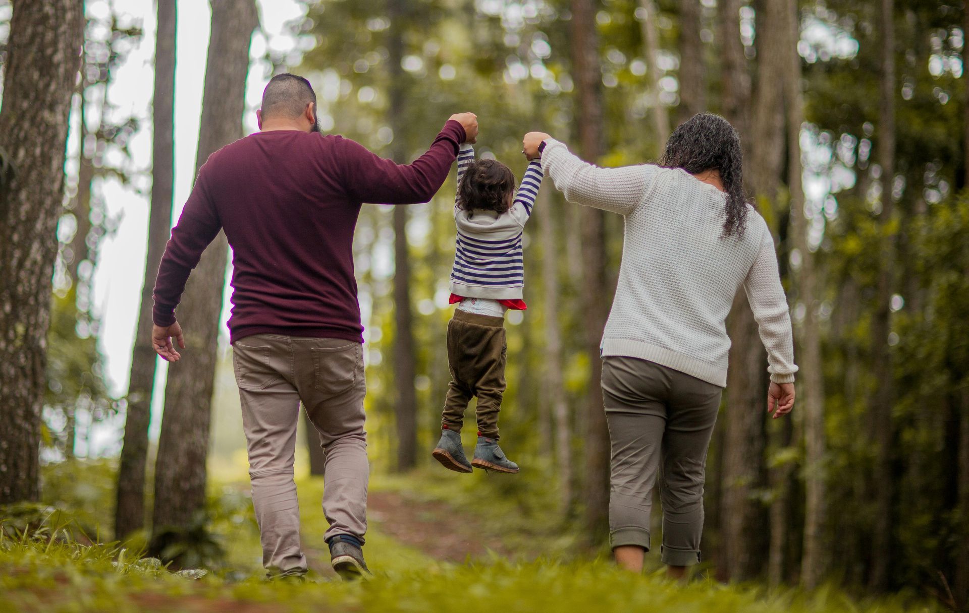 Parents walking in the woods with their young child. 