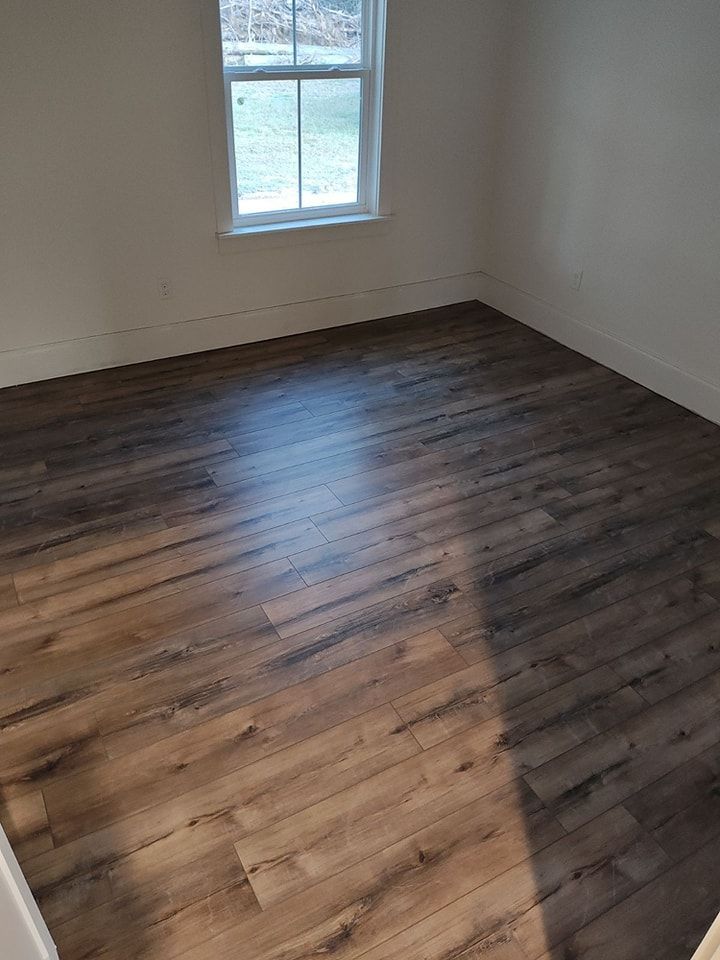 A bedroom with hardwood floors and a window.