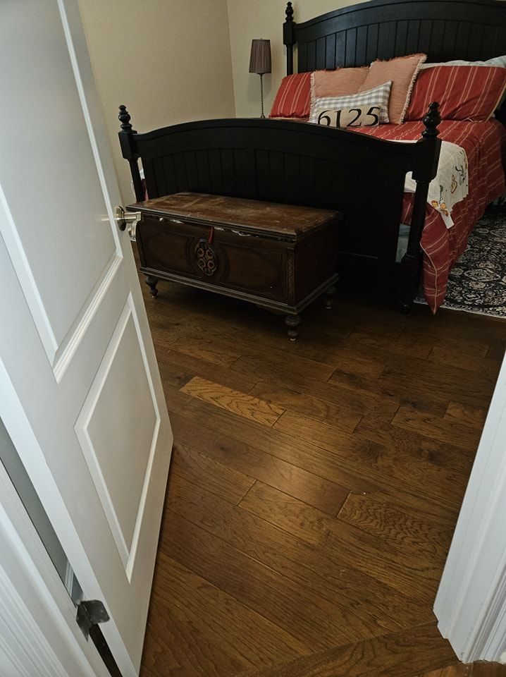 A bedroom with a bed and a trunk on the floor.