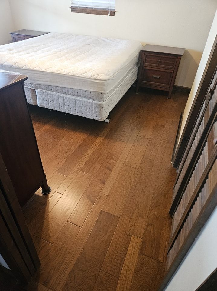 A bedroom with hardwood floors and a bed.