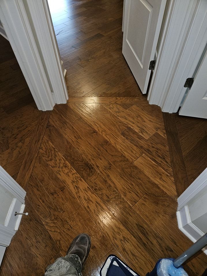 A person is mopping a wooden floor in a hallway.