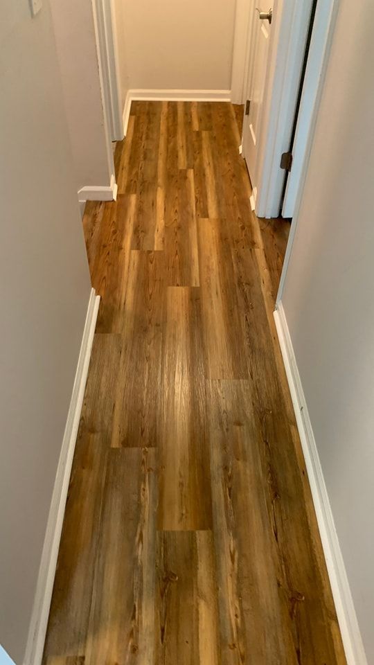 A hallway with hardwood floors and white trim in a house.