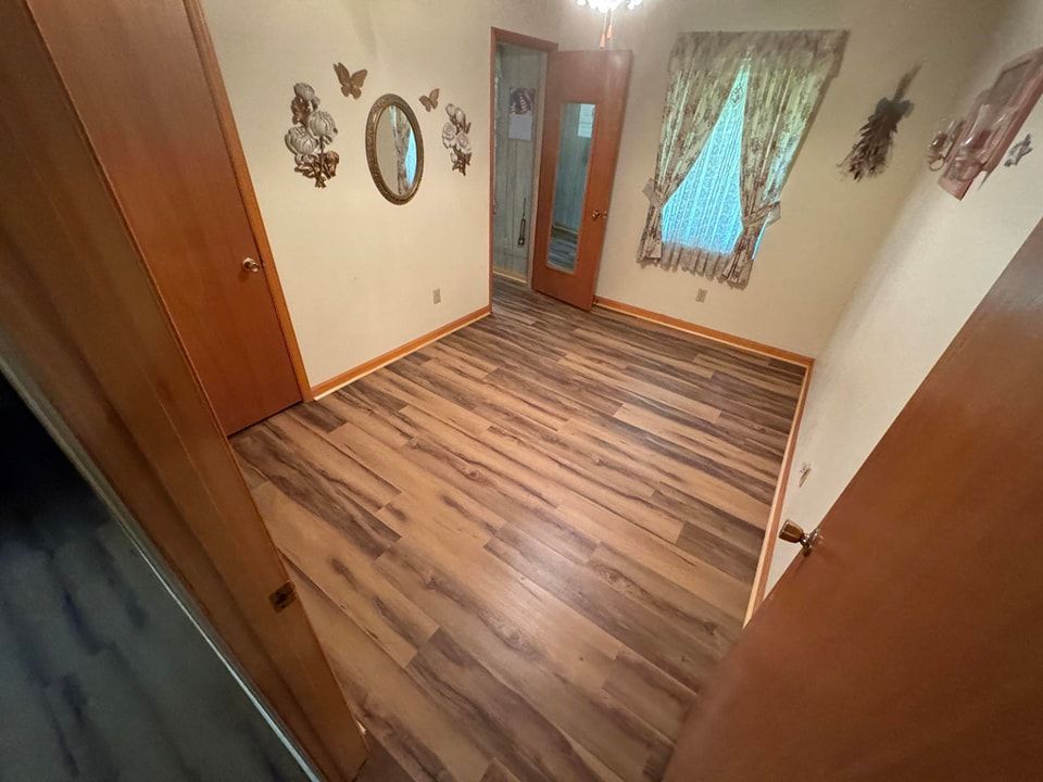 A room with hardwood floors and a mirror on the wall.