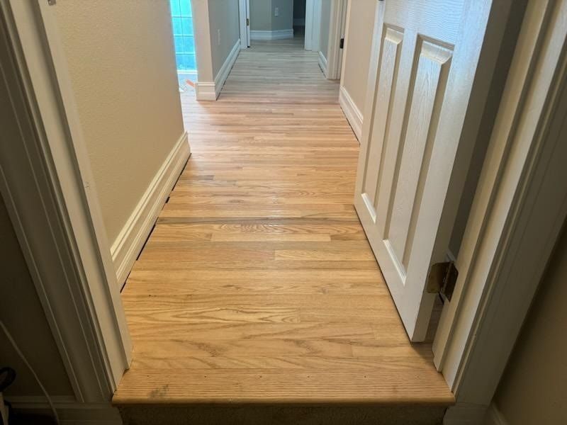 A hallway with hardwood floors and stairs in a house.
