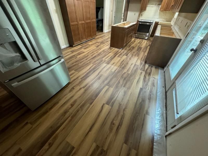 A kitchen with hardwood floors and a stainless steel refrigerator.
