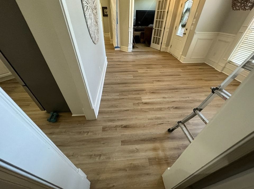 A hallway with a wooden floor and a ladder in it.