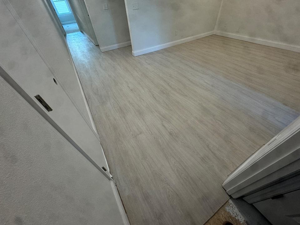 A room with a white wooden floor and a hallway.