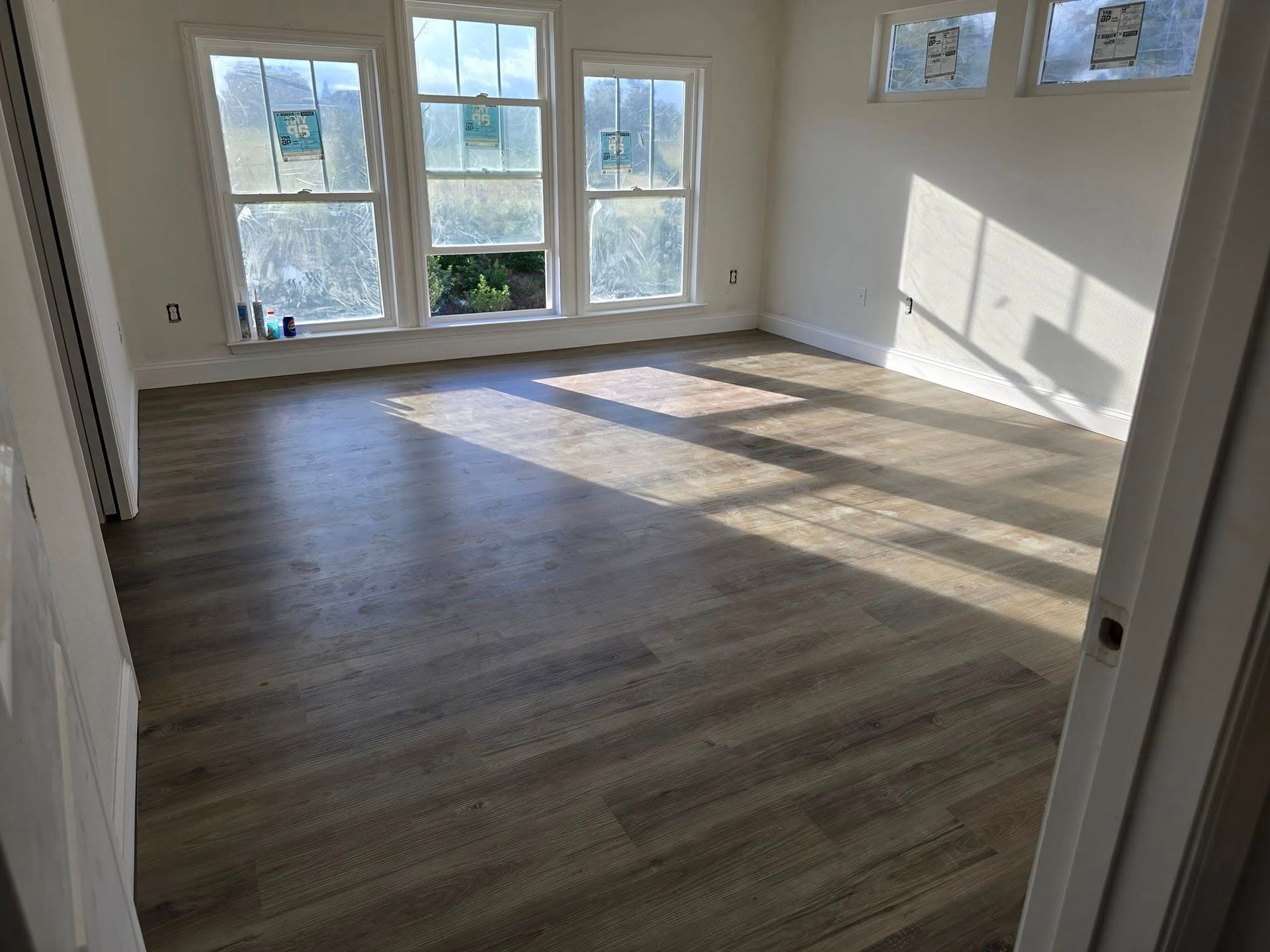 A large empty room with hardwood floors and three windows.