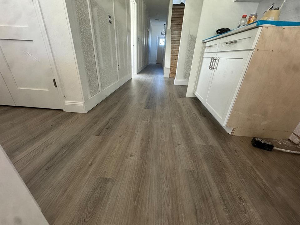 A hallway with hardwood floors and white cabinets in a house.