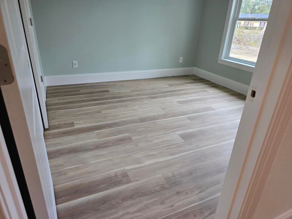 A bedroom with hardwood floors and a window.