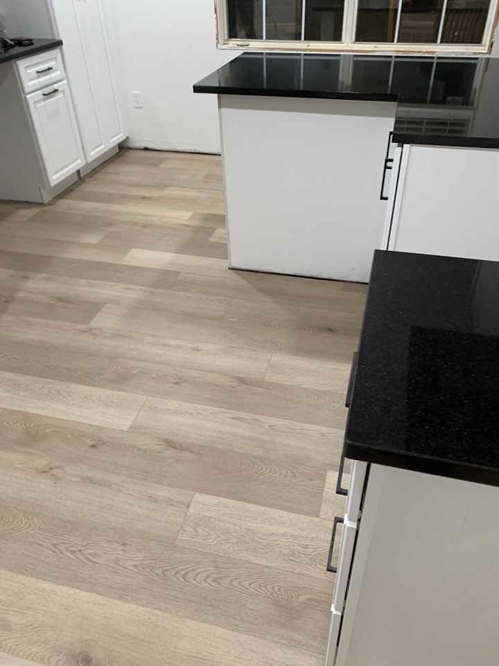 A kitchen with hardwood floors and a black counter top.