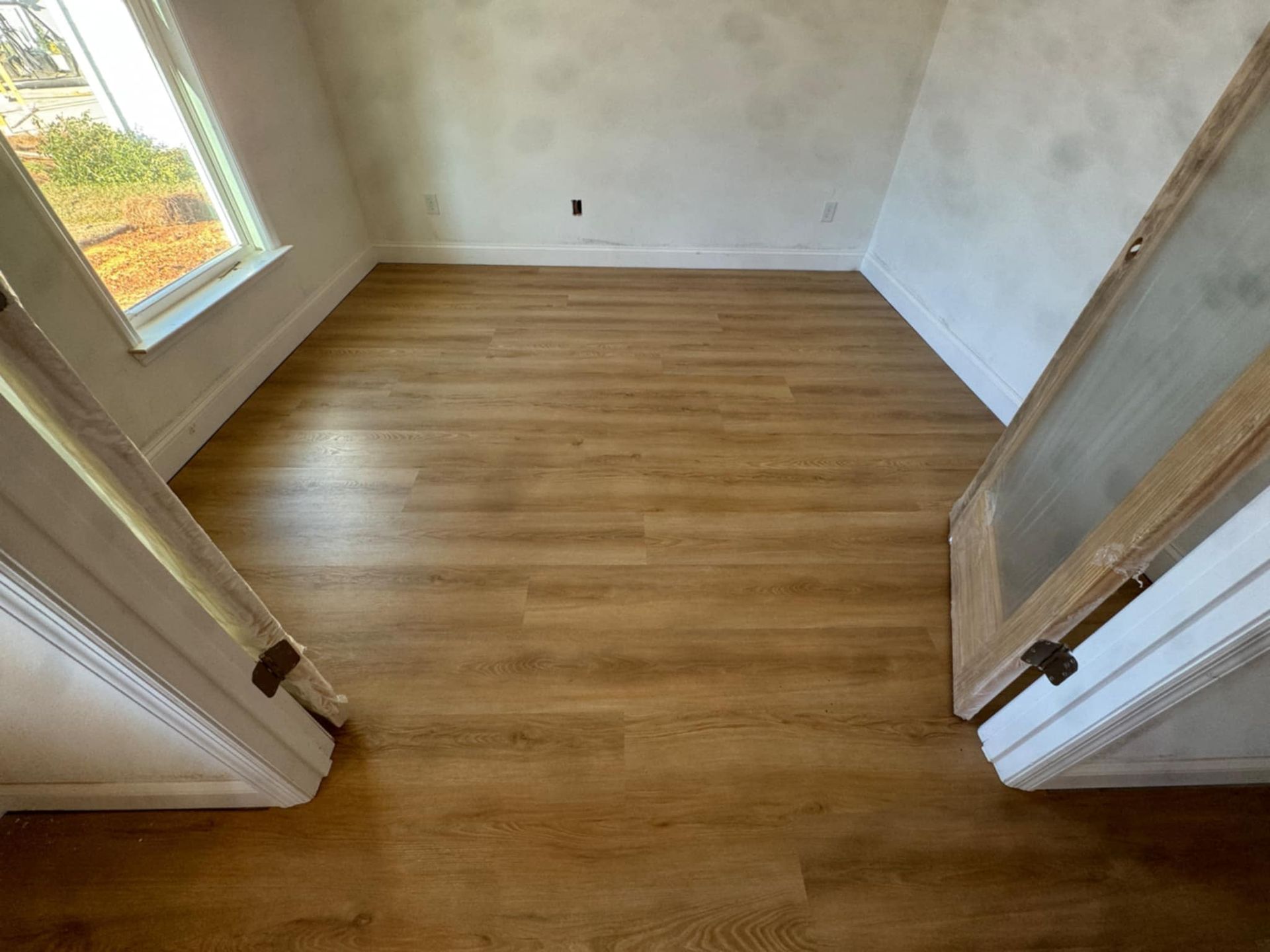 A room with a wooden floor and two doors.