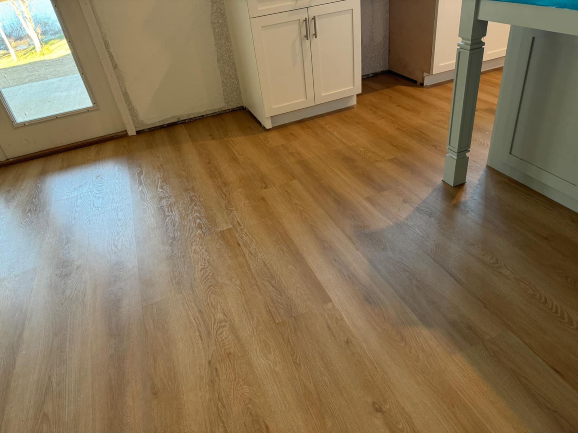 A kitchen with a wooden floor and white cabinets.