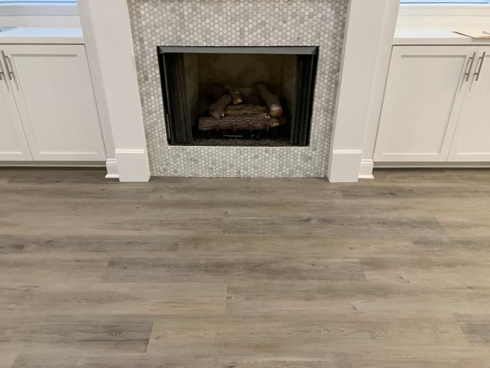 A fireplace with a wooden floor and white cabinets in a living room.