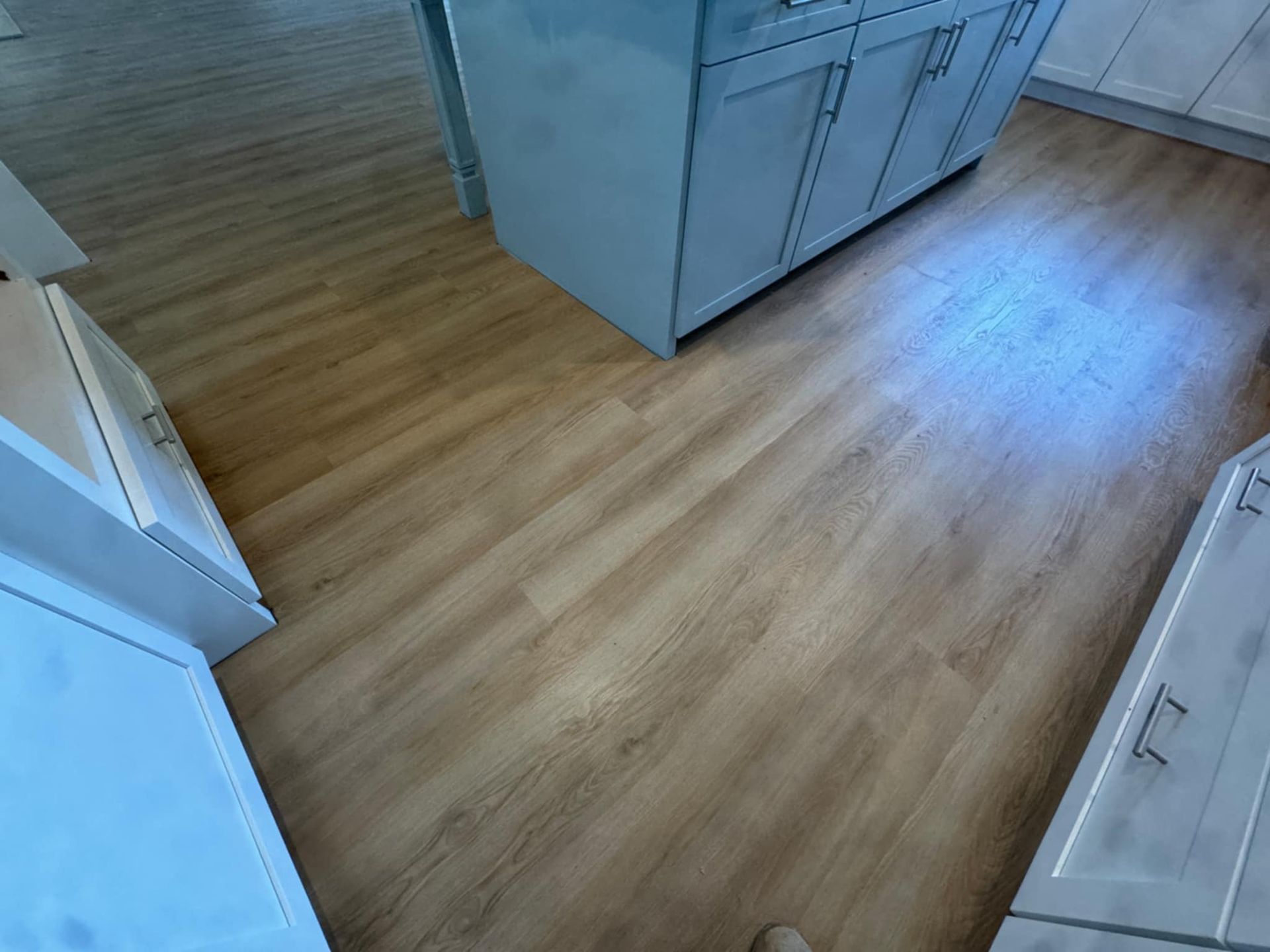 A kitchen with a wooden floor and white cabinets.