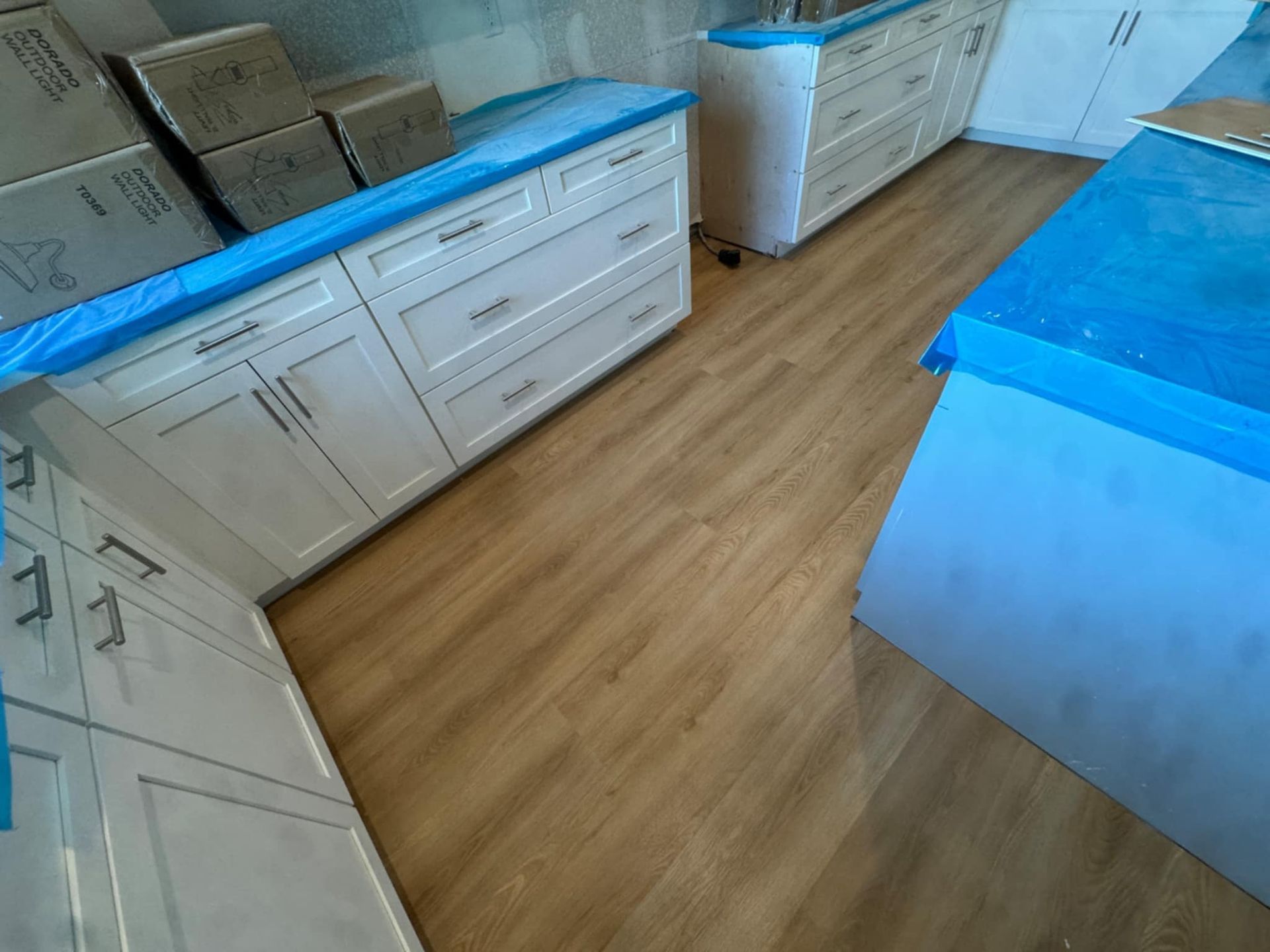 A kitchen with white cabinets and wooden floors is being remodeled.