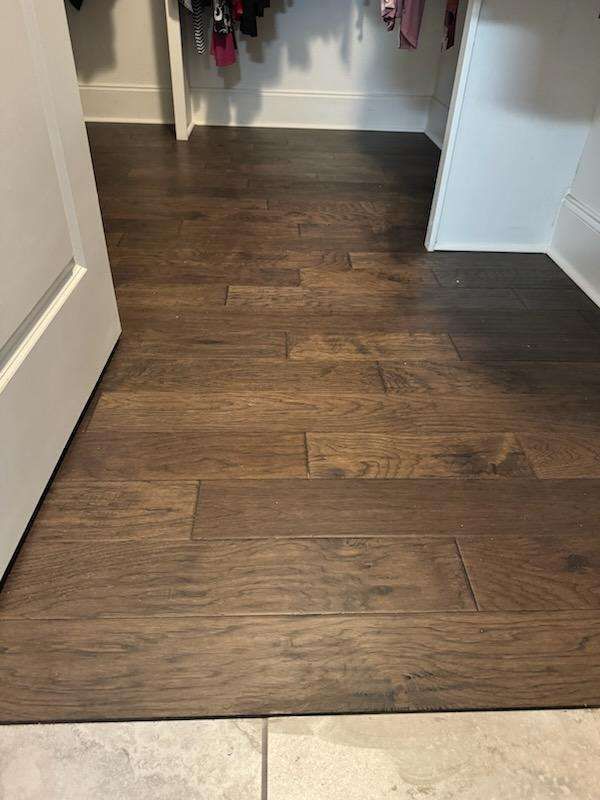 A wooden floor in a closet next to a door.