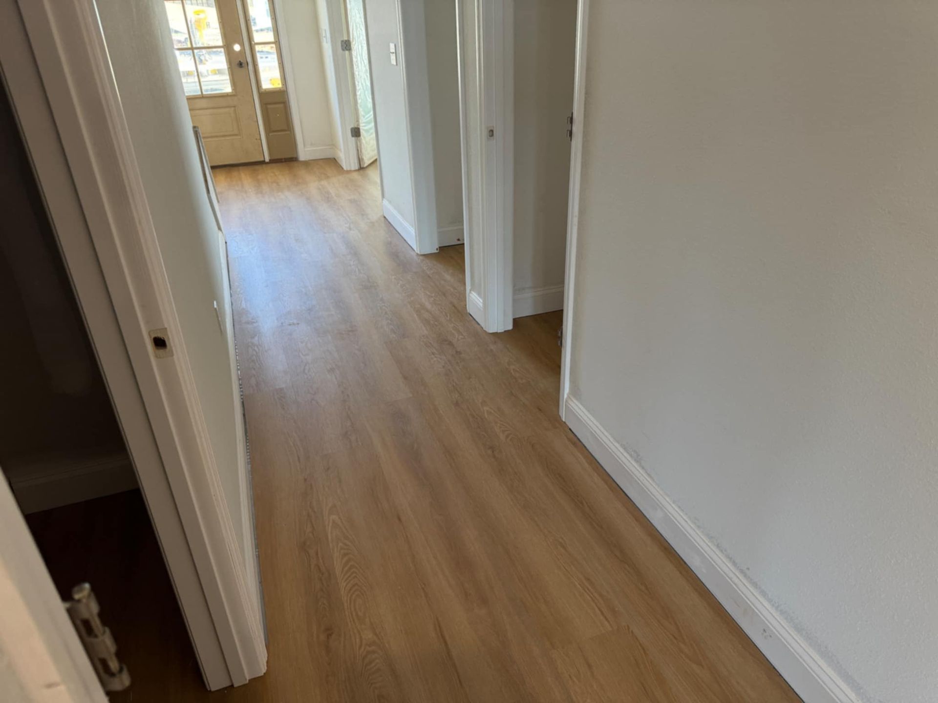 A hallway with hardwood floors and white walls in a house.