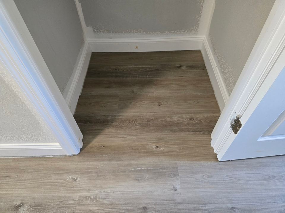 A closet with a wooden floor and two doors.