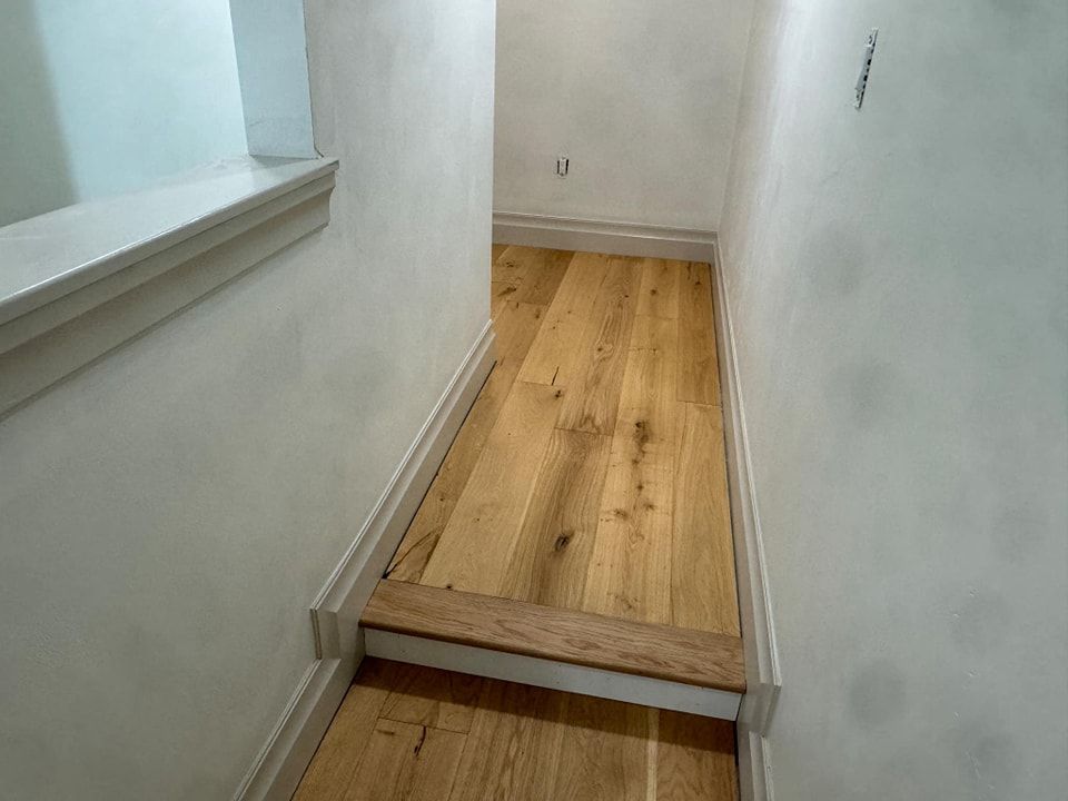 A hallway with wooden floors and white walls.