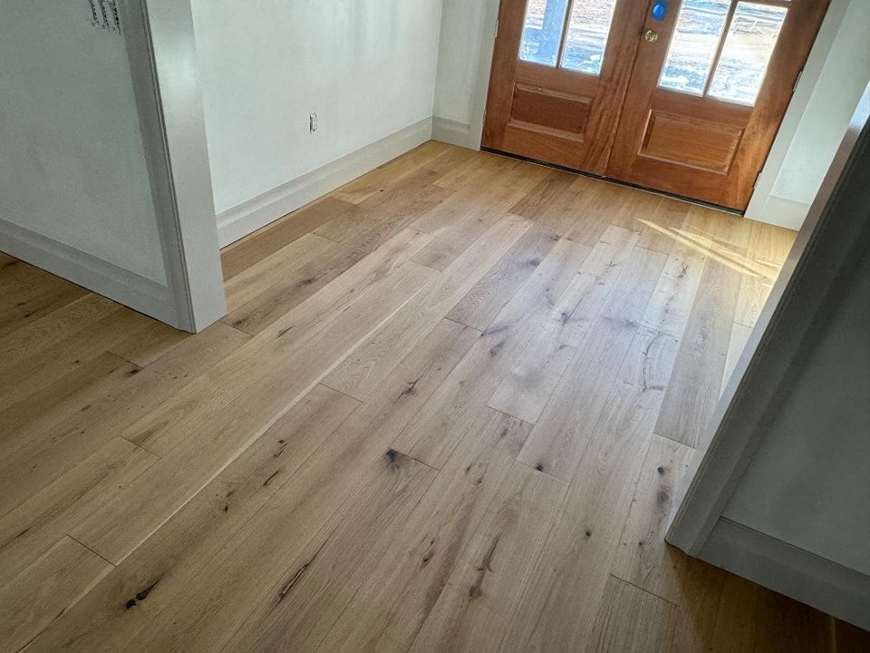 A hallway with hardwood floors and a wooden door.