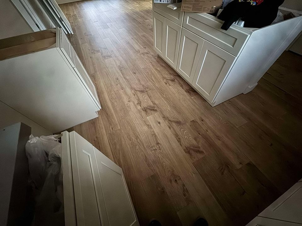 A kitchen with hardwood floors and white cabinets.